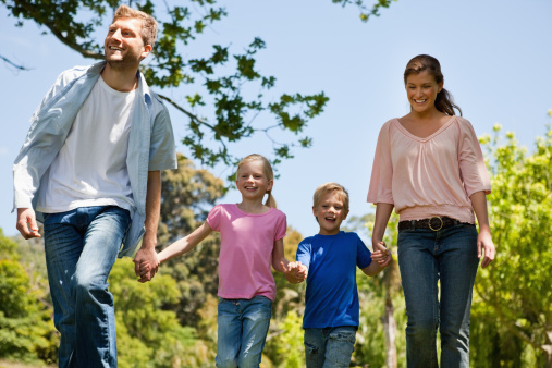 Family of four walking outside holding hands